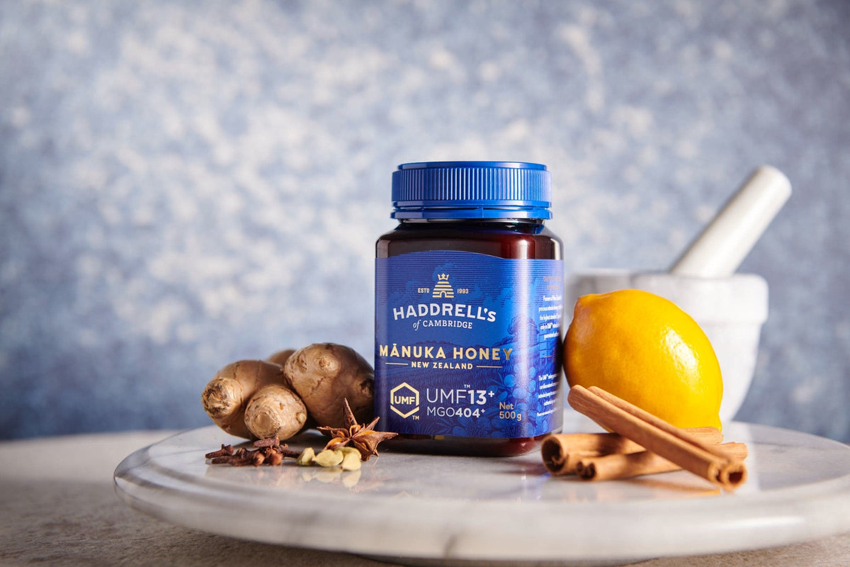Miód manuka Haddrell's UMF 13⁺ w słoiku 500 g obok cytryny, imbiru i cynamonu