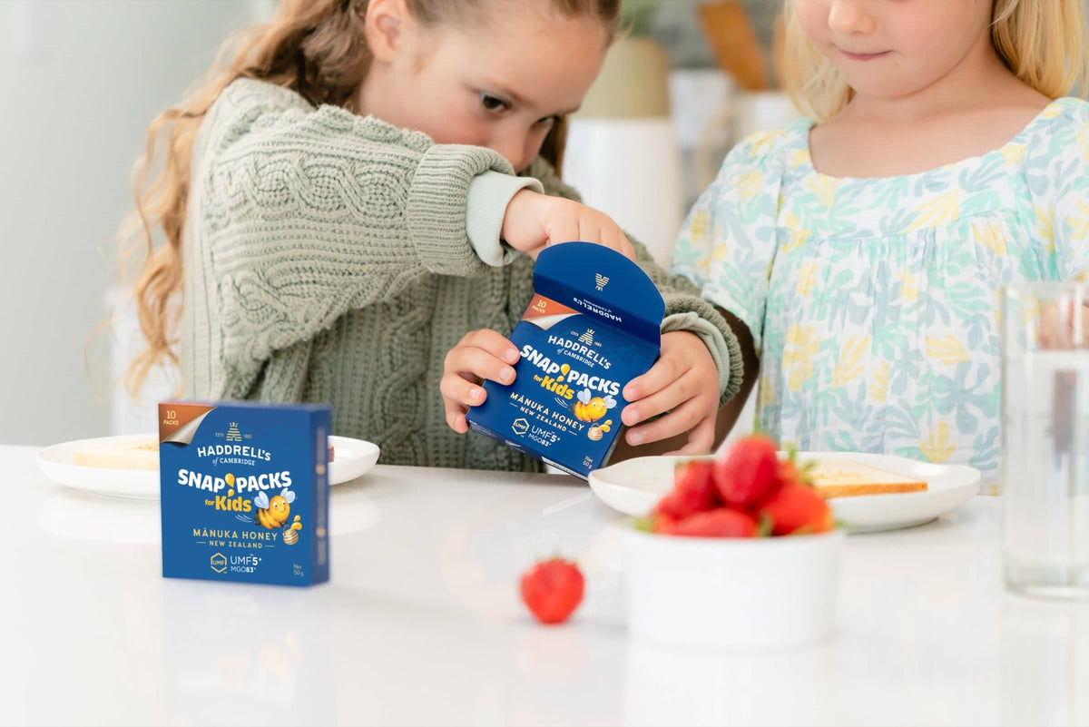 Dziecko otwiera opakowanie Snap Packs for Kids z miodem manuka Haddrell's UMF 5⁺